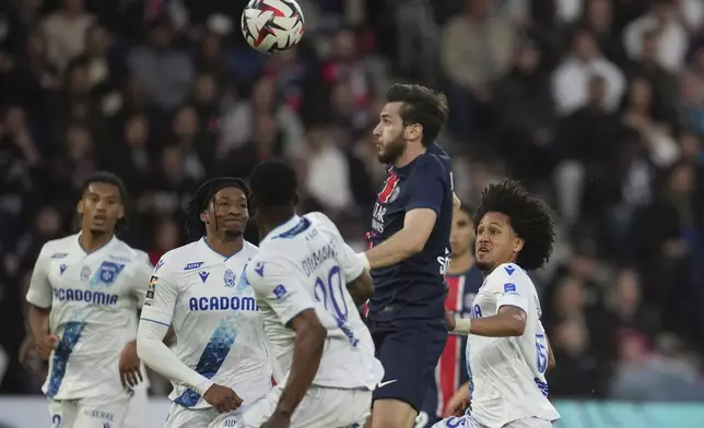 PSG's Khvicha Kvaratskhelia, top centre right, jumps for the ball during the French League One soccer match between Paris Saint-Germain and Auxerre at the Parc des Princes stadium in Paris, Saturday, May 17, 2025. (AP Photo/Christophe Ena)