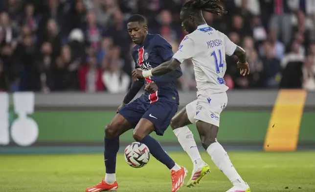 PSG's Ousmane Dembele, left, challenges for the ball with Auxerre's Gideon Mensah during the French League One soccer match between Paris Saint-Germain and Auxerre at the Parc des Princes stadium in Paris, Saturday, May 17, 2025. (AP Photo/Christophe Ena)