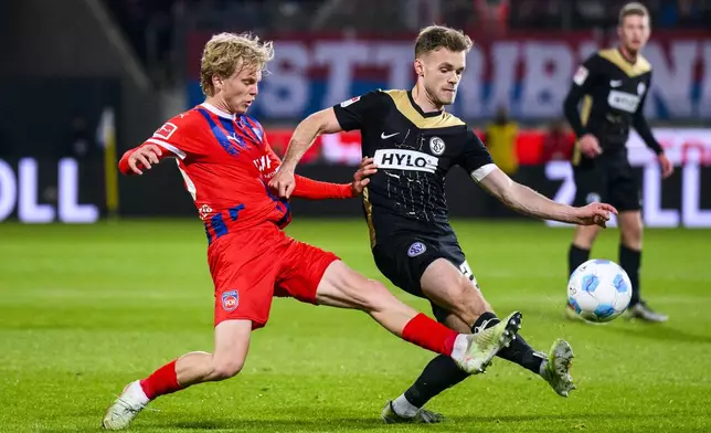 Heidenheim's Frans Krätzig, left, and Elversberg's Tom Zimmerschied battle for the ball during a Bundesliga relegation playoff first leg soccer match between FC Heidenheim and SV Elversberg, Thursday, May 22, 2025, in Heidenheim, Germany. (Tom Weller/dpa via AP)