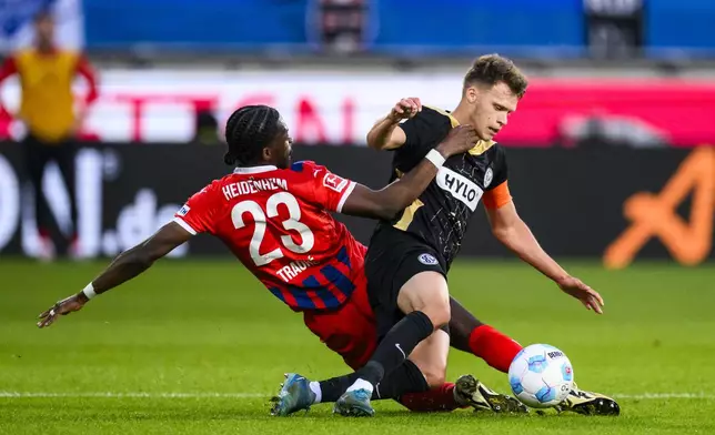 Heidenheim's Omar Traore, left, and Elversberg's Robin Fellhauer battle for the ball during a Bundesliga relegation playoff first leg soccer match between FC Heidenheim and SV Elversberg, Thursday, May 22, 2025, in Heidenheim, Germany. (Tom Weller/dpa via AP)