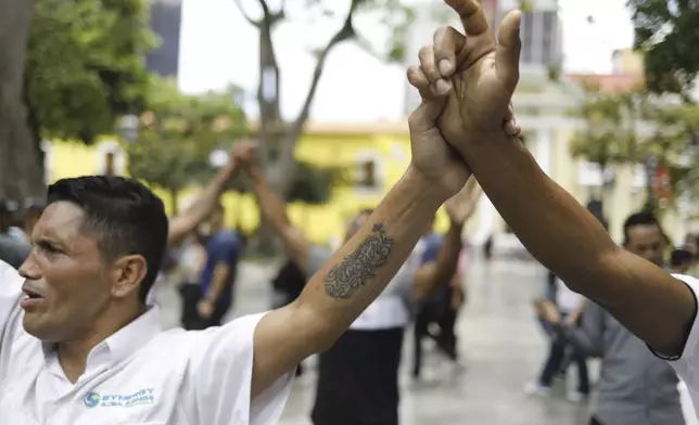 Jose Ramirez, donning a Jesus Christ tattoo, joins hands in prayer with fellow worshippers during an evangelical service in a downtown square of Caracas, Venezuela, Friday, April 18, 2025.(AP Photo/Cristian Hernandez)