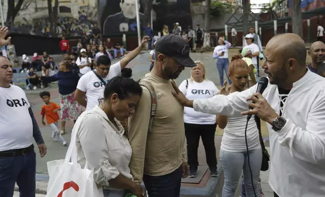 Pastor Siro Salazar preaches to a couple from the "Nosotros Unidos" rehab center during an evangelical service in a downtown square of Caracas, Venezuela, Saturday, April 5, 2025. (AP Photo/Cristian Hernandez)
