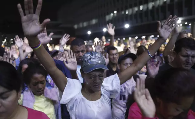 Evangelicals lift their hands in prayer during an outdoor service in a downtown square of Caracas, Venezuela, Saturday, April 12, 2025. (AP Photo/Cristian Hernandez)