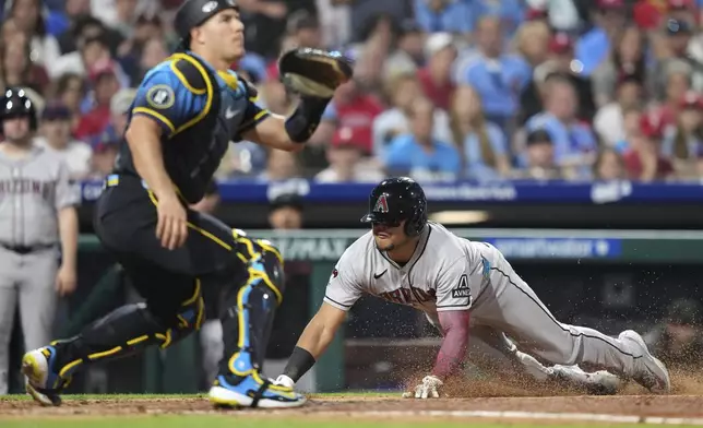 Arizona Diamondbacks' Gabriel Moreno, right, scores past Philadelphia Phillies catcher J.T. Realmuto on a single by Lourdes Gurriel Jr. during the sixth inning of a baseball game, Friday, May 2, 2025, in Philadelphia. (AP Photo/Matt Slocum)