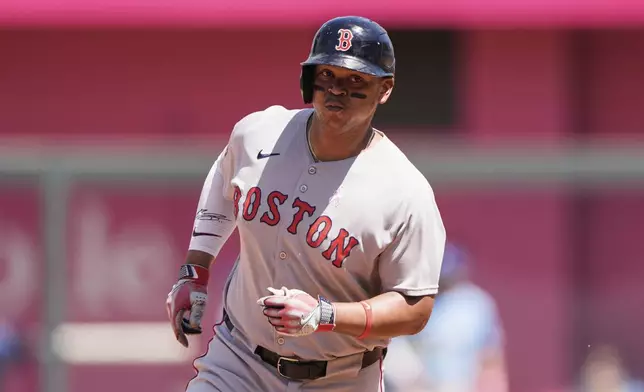 Boston Red Sox's Rafael Devers, right, runs home to score after hitting a two-run home run during the sixth inning of a baseball game against the Kansas City Royals, Sunday, May 11, 2025, in Kansas City, Mo. (AP Photo/Charlie Riedel)