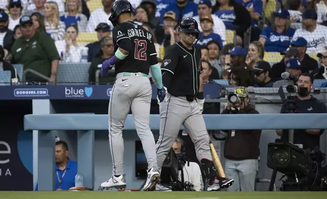 Arizona Diamondbacks' Lourdes Gurriel Jr., left, celebrates after scoring on an RBI groundout by Josh Naylor during the first inning of a baseball game against the Los Angeles Dodgers in Los Angeles, Monday, May 19, 2025. (AP Photo/Kyusung Gong)