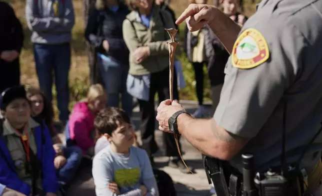 Park ranger Jesse Anderson shows a pitcher plant to visitors during a weekly carnivorous plant hike Saturday, March 22, 2025, in Carolina Beach, N.C. (AP Photo/Erik Verduzco)
