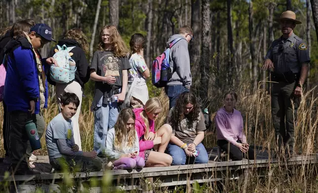 Park ranger Jesse Anderson, right, speaks to visitors during a weekly carnivorous plant hike Saturday, March 22, 2025, in Carolina Beach, N.C. (AP Photo/Erik Verduzco)