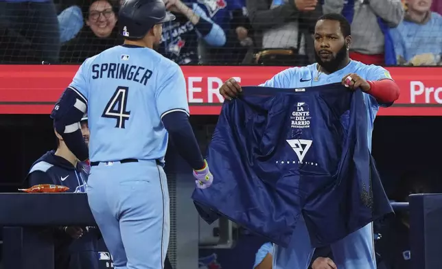 Toronto Blue Jays' George Springer (4) celebrates his solo home run against the Athletics with Vladimir Guerrero Jr. during the third inning of a baseball game in Toronto, Thursday, May 29, 2025. (Nathan Denette/The Canadian Press via AP)