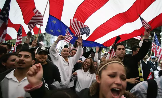 FILE - Participants in an immigration rights rally walk under a giant American flag during a march through downtown Chicago, May 1, 2006. (AP Photo/M. Spencer Green, File)