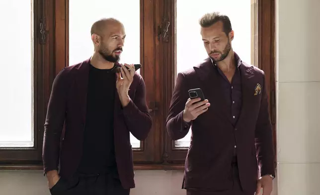 FILE - Andrew Tate, left, and his brother Tristan, right, wait at the Court of Appeals building in Bucharest, Romania, on Oct. 15, 2024. (AP Photo/Vadim Ghirda, File)