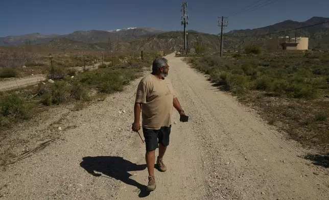 Glenn Chavez sets the distance for which a helicopter pilot can remotely turn on a Heli-Hydrant, a small, open tank that helicopters can rely on to get water faster for urban fires, Friday, April 11, 2025, in Cabazon, Calif. (AP Photo/Brittany Peterson)