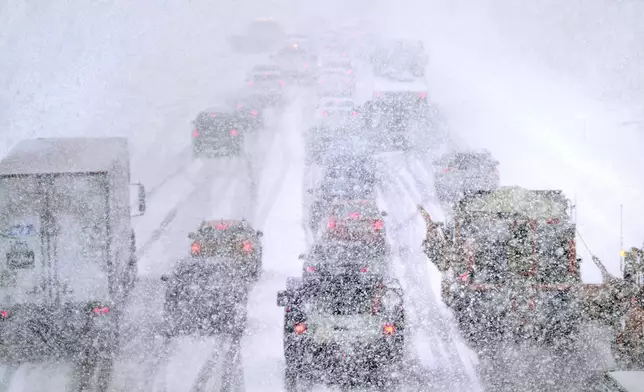 FILE - Plows, at right, try to pass nearly stopped traffic, due to weather conditions, on Route 93 South, March 14, 2023, in Londonderry, N.H. (AP Photo/Charles Krupa, file)