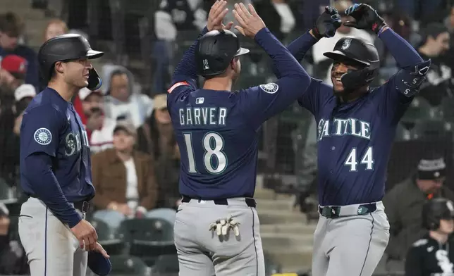 Seattle Mariners' Julio Rodríguez (44) celebrates with Ben Williamson, left, and Mitch Garver (18) after hitting a grand slam during the eighth inning of a baseball game against the Chicago White Sox in Chicago, Monday, May 19, 2025. (AP Photo/Nam Y. Huh)