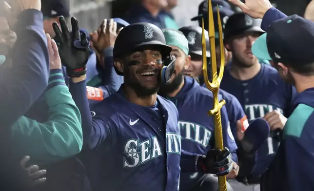 Seattle Mariners' Julio Rodríguez celebrates with teammates in the dugout after hitting a grand slam during the eighth inning of a baseball game against the Chicago White Sox in Chicago, Monday, May 19, 2025. (AP Photo/Nam Y. Huh)