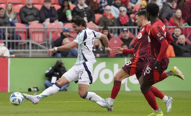 New England Revolution forward Leonardo Campana (9) shoots to score under pressure from Toronto FC defender Raoul Petretta (28) and teammate Nicksoen Gomis (15) during the first half of an MLS soccer game in Toronto, Saturday, May 3, 2025. (Frank Gunn/The Canadian Press via AP)