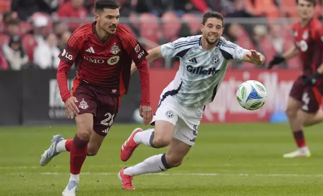 Toronto FC defender Raoul Petretta, left, moves the ball under pressure from New England Revolution midfielder Matt Polster (8) during the first half of an MLS soccer game in Toronto, Saturday, May 3, 2025. (Frank Gunn/The Canadian Press via AP)