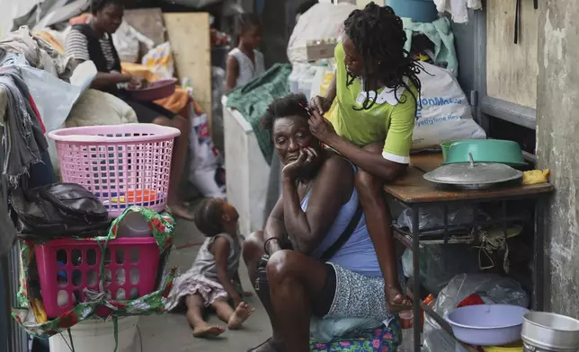 A woman combs the hair of another at a shelter for families displaced by gang violence, in Port-au-Prince, Haiti, Thursday, May 22, 2025. (AP Photo/Odelyn Joseph)