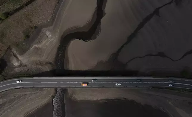 Traffic crosses a bridge at Woodhead Reservoir in Derbyshire as England experiences a significant drought, with reservoir levels at 84% of capacity, lower than the 90% seen in 2022, in Woodhead, England, Monday, May 19, 2025. (AP Photo/Jon Super)