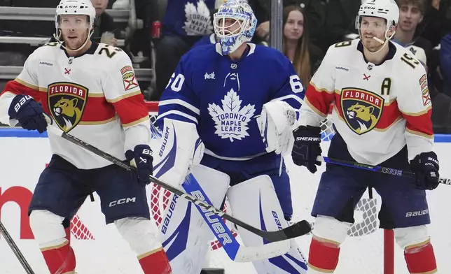 Toronto Maple Leafs goaltender Joseph Woll (60) looks through Florida Panthers' Carter Verhaeghe (23) and Matthew Tkachuk (19) during second period NHL playoff hockey action in Toronto on Wednesday, May 7, 2025. (Frank Gunn/The Canadian Press via AP)