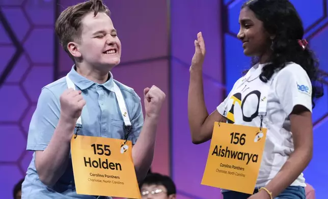 Holden Connor Good, 13, left, reacts after spelling a word correctly as Aishwarya Kallakuri, 14, of Charlotte, N.C., right, looks on during the semifinals of the Scripps National Spelling Bee, Wednesday, May 28, 2025, in Oxon Hill, Md. (AP Photo/Julia Demaree Nikhinson)
