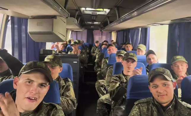 In this photo taken from video distributed by Russian Defense Ministry Press Service on Tuesday, May 6, 2025, a group of Russian soldiers applaud as they sit in a bus after being released in a prisoners swap between Russia and Ukraine, at the Ukraine-Belarusian boarder. (Russian Defense Ministry Press Service via AP)