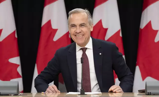 Prime Minister Mark Carney smiles as he takes his seat at his first news conference since winning the federal election, in Ottawa, Friday, May 2, 2025. (Adrian Wyld /The Canadian Press via AP)