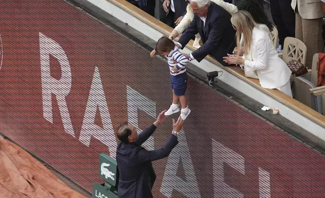 Rafa Nadal reaches for his son Rafael Junior during a farewell ceremony at center court Philippe-Chatrier, at the Roland-Garros stadium, in Paris, Sunday May 25, 2025. (AP Photo/Christophe Ena)