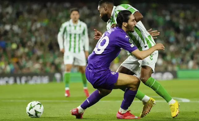Fiorentina's Yacine Adli, lwft, and Betis' Cedric Bakambu fight for the ball during the Conference League semifinal first leg soccer match between Betis and Fiorentina at the Benito Villamarin stadium in Seville, Spain, Thursday, May 1, 2025. (AP Photo/Jose Breton)