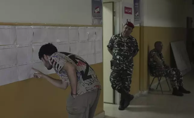 A Lebanese man checks a polling list for his name before voting at a polling station during municipal elections in the southern suburbs of Beirut, Lebanon, Sunday, May 4, 2025. (AP Photo/Hassan Ammar)