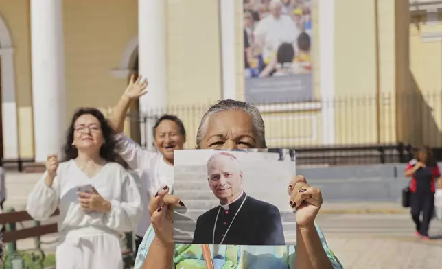 Faithful hold a photo of Bishop Robert Prevost, who was elected Pope Leo XIV, in front of the Cathedral of Chiclayo, Peru, Tuesday, May 8, 2025, where he served as bishop for several years, (AP Photo/Manuel Medina)