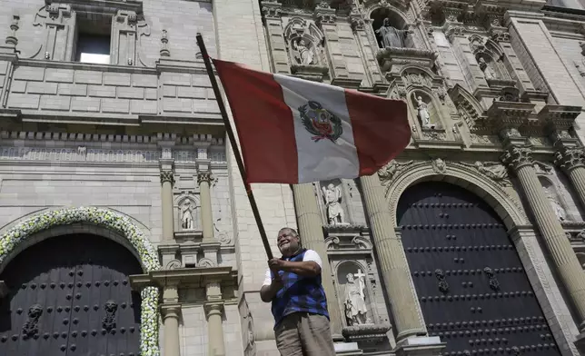 A man waves a Peruvian flag in front of the Cathedral after Cardinal Robert Prevost was elected as the new pope taking the name Leo XIV, in Lima, Peru, Thursday, May 8, 2025. (AP Photo/Cesar Zamalloa)
