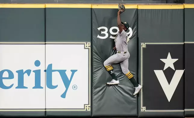 Athletics center fielder Denzel Clarke (1) tries to reach for Houston Astros' Jose Altuve's two-run home run during the fourth inning of a baseball game, Tuesday, May 27, 2025, in Houston. (AP Photo/Karen Warren)