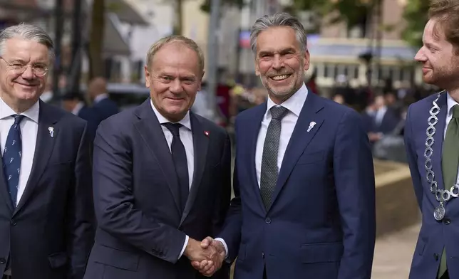 Poland's Prime Minister Donald Tusk, center left, is greeted by Netherlands' Prime Minister Dick Schoof, center right, as dozens of World War II veterans gathered for Liberation Day celebrations in Wageningen, Netherlands, Monday, May 5, 2025. (AP Photo/Peter Dejong)