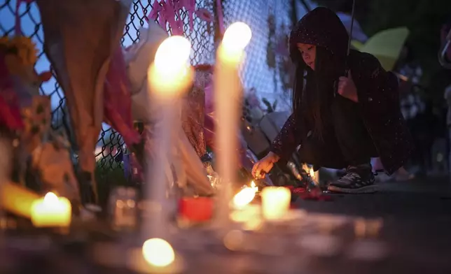 A young girl lights a candle during a vigil on a provincial day of mourning for the victims of the vehicle-ramming attack at the Filipino community's Lapu Lapu Day festival last week, in Vancouver, on Friday, May 2, 2025. (Darryl Dyck/The Canadian Press via AP)