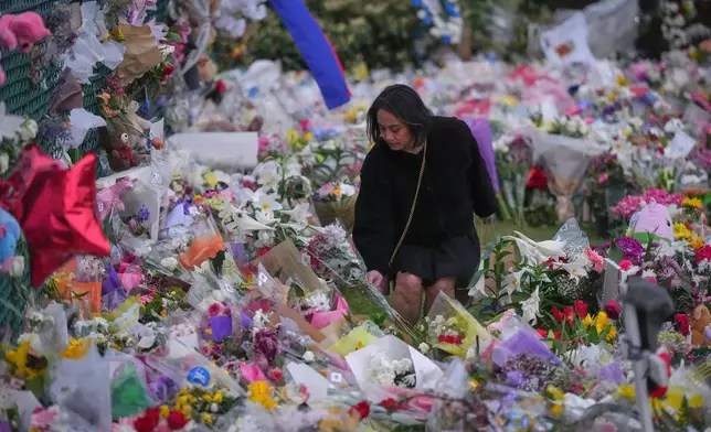 A woman lays flowers at a memorial during a vigil on a provincial day of mourning for the victims of the vehicle-ramming attack at the Filipino community's Lapu Lapu Day festival last week in Vancouver, on Friday, May 2, 2025. (Darryl Dyck/The Canadian Press via AP)
