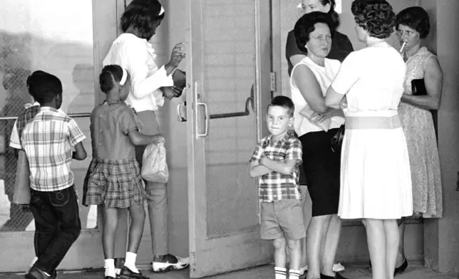 FILE - A group of African American students, left, enter the Boothville-Venice School in Plaquemines Parish, Louisiana on Sept. 12, 1966 as a group of white mothers wait at the entrance of the school. (AP Photo/Jack Thornell, file)