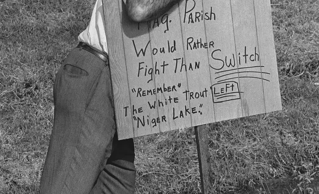 FILE - A man plants a sign reading outside Woodlawn High School in Pointe a la Hache, Louisiana on Sept. 1, 1966 where five African Americans applied for registration for the first time in parish history. (AP Photo/Jack Thornell, file)