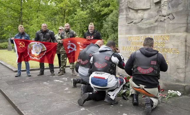 Participants of the Russian motorcycle club "Night Wolves" kneel in front of Friedrich Press' obelisk during a wreath-laying ceremony at the Soviet garrison cemetery in Dresden, Germany, Wednesday May 7, 2025, as these days mark the 80th anniversary of the end of the Second World War. (Sebastian Kahnert/dpa via AP)