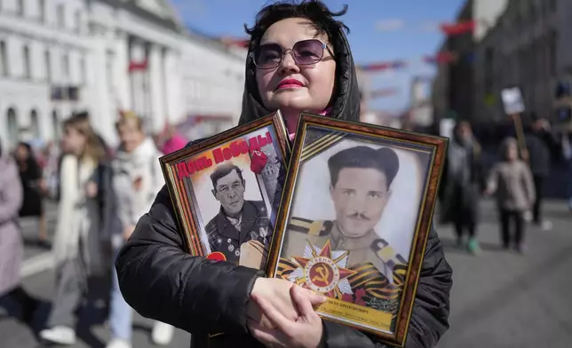 A woman carries portraits of her relatives who fought in World War II, during the Immortal Regiment march at the Nevsky prospect, the central avenue of St. Petersburg, Russia, Friday, May 9, 2025, during celebrations of the 80th anniversary of the Soviet Union's victory over Nazi Germany during the World War II. (AP Photo/Dmitri Lovetsky)