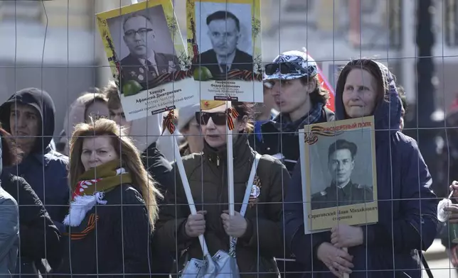 People holding portraits of relatives who fought in World War II, watch a concert at the Palace Square after during the Immortal Regiment march in St. Petersburg, Russia, Friday, May 9, 2025, during celebrations of the 80th anniversary of the Soviet Union's victory over Nazi Germany during the World War II. (AP Photo/Dmitri Lovetsky)