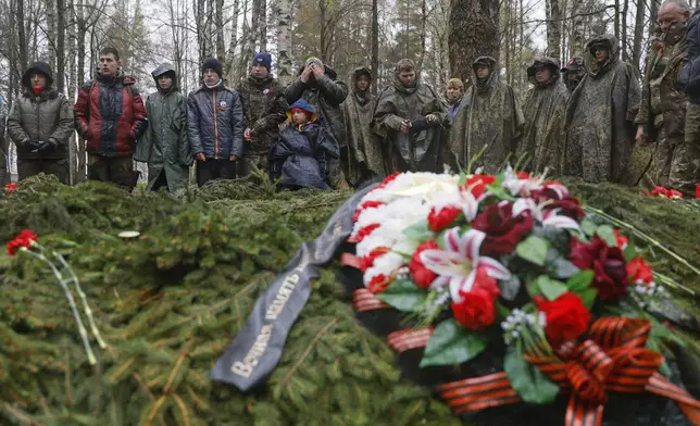 Members of volunteer search teams stand around the mass grave with the remains of Soviet soldiers killed during World War II, during a reburial ceremony at the Sinyavino Heights memorial near the village of Sinyavino, 50 km (31 miles) east of St. Petersburg, Russia, Wednesday, May 7, 2025, ahead of celebrations of the 80th anniversary of the Soviet Union's victory over Nazi Germany during the World War II. (AP Photo/Elena Ignatyeva)