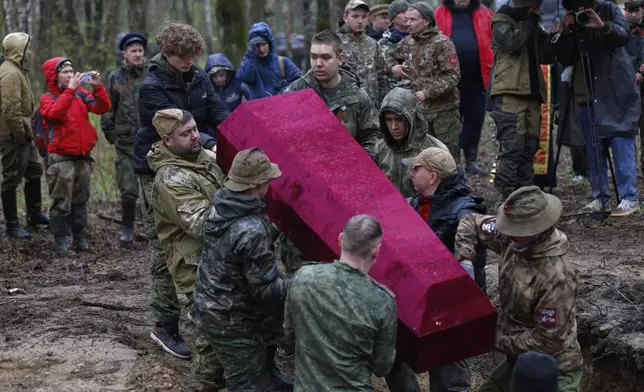 Members of volunteer search teams lower the coffin with the remains of Soviet soldiers killed during World War II into a mass grave, during a reburial ceremony at the Sinyavino Heights memorial near the village of Sinyavino, 50 km (31 miles) east of St. Petersburg, Russia, Wednesday, May 7, 2025, ahead of celebrations of the 80th anniversary of the Soviet Union's victory over Nazi Germany during the World War II. (AP Photo/Elena Ignatyeva)