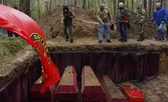 Members of volunteer search teams walk past the mass grave with the remains of Soviet soldiers killed during World War II, during a reburial ceremony at the Sinyavino Heights memorial near the village of Sinyavino, 50 km (31 miles) east of St. Petersburg, Russia, Wednesday, May 7, 2025, ahead of celebrations of the 80th anniversary of the Soviet Union's victory over Nazi Germany during the World War II. (AP Photo/Elena Ignatyeva)