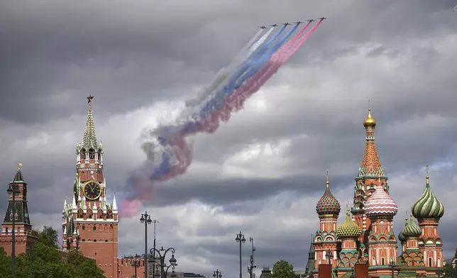 Russian Air Force Su-25 jets fly over Red Square leaving trails of smoke in the colours of the Russian national flag during the Victory Day military parade rehearsal with the Spasskaya Tower, left, and the St. Basil's Cathedral, right, in Moscow, Russia, on Monday, May 5, 2025, marking the 80th anniversary of the end of World War II. (AP Photo/Alexander Zemlianichenko)