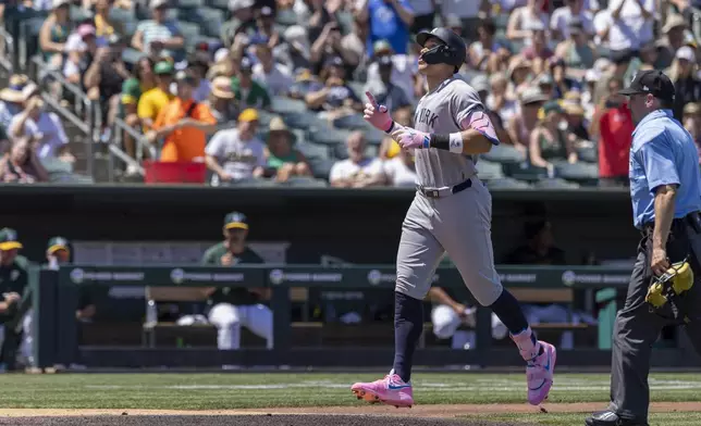 New York Yankees' Aaron Judge, left, points skyward after hitting a solo home run during the fourth inning of a baseball game against the Athletics, Saturday, May 10, 2025, in West Sacramento, Calif. (AP Photo/Sara Nevis)