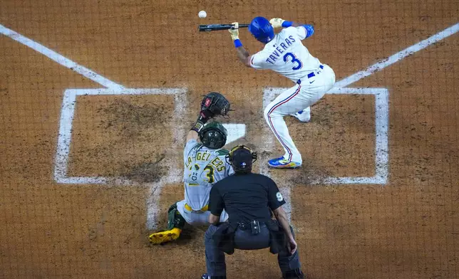 Texas Rangers' Leody Taveras (3) drops a sacrifice bunt in front of Oakland Athletics catcher Shea Langeliers (23) and home plate umpire James Hoye during the third inning of a baseball game Wednesday, April 30, 2025, in Arlington, TX. (AP Photo/Julio Cortez)