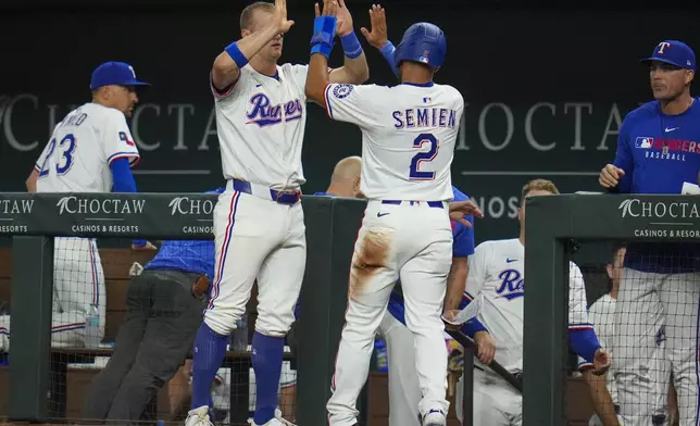 Texas Rangers' Marcus Semien (2) is greeted near the dugout by Josh Jung after scoring on a single by Adolis García against the Oakland Athletics during the fourth inning of a baseball game Wednesday, April 30, 2025, in Arlington, TX. (AP Photo/Julio Cortez)
