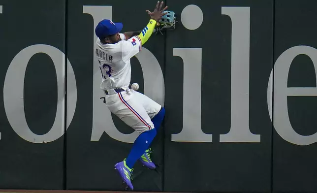 Texas Rangers outfielder Adolis García crashes with the wall while chasing a double by Oakland Athletics' JJ Bleday during the third inning of a baseball game Wednesday, April 30, 2025, in Arlington, TX. (AP Photo/Julio Cortez)