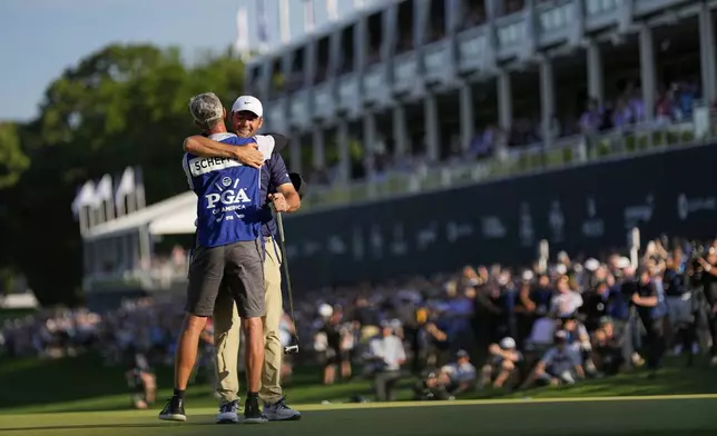 Scottie Scheffler hugs his caddie Ted Scott after winning the PGA Championship golf tournament at the Quail Hollow Club, Sunday, May 18, 2025, in Charlotte, N.C. (AP Photo/George Walker IV)